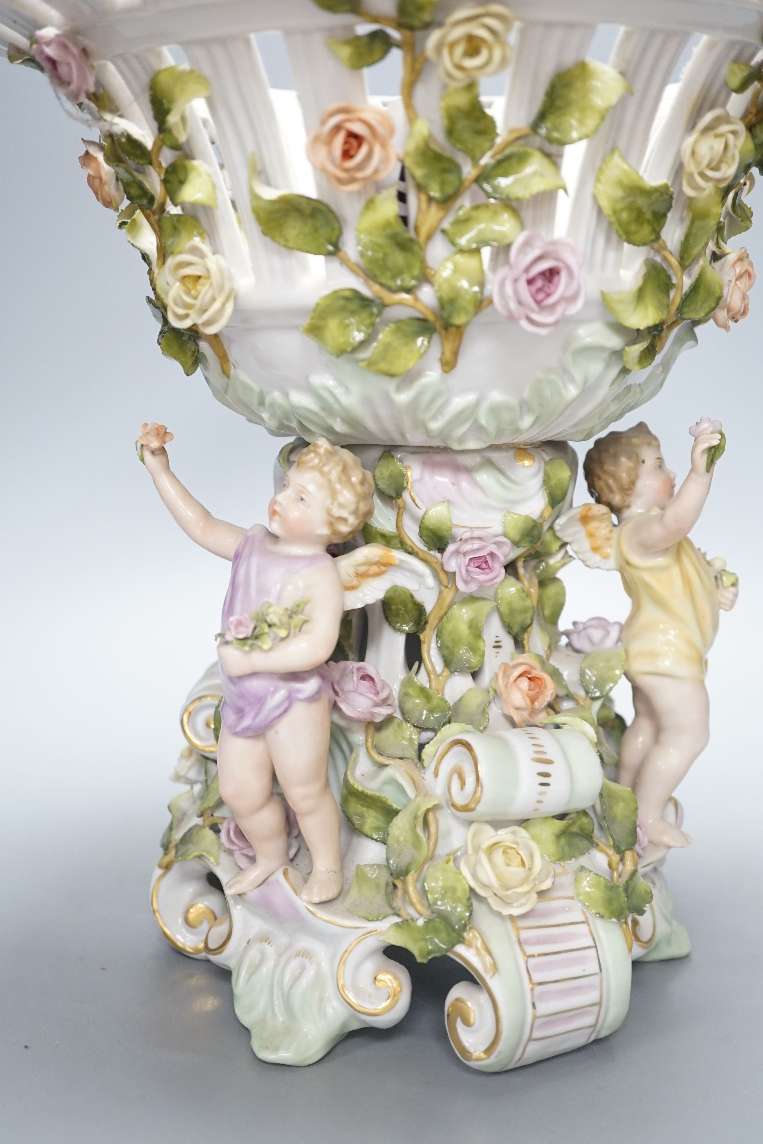 A German porcelain floral encrusted fruit stand, on a figural base, 30cm tall